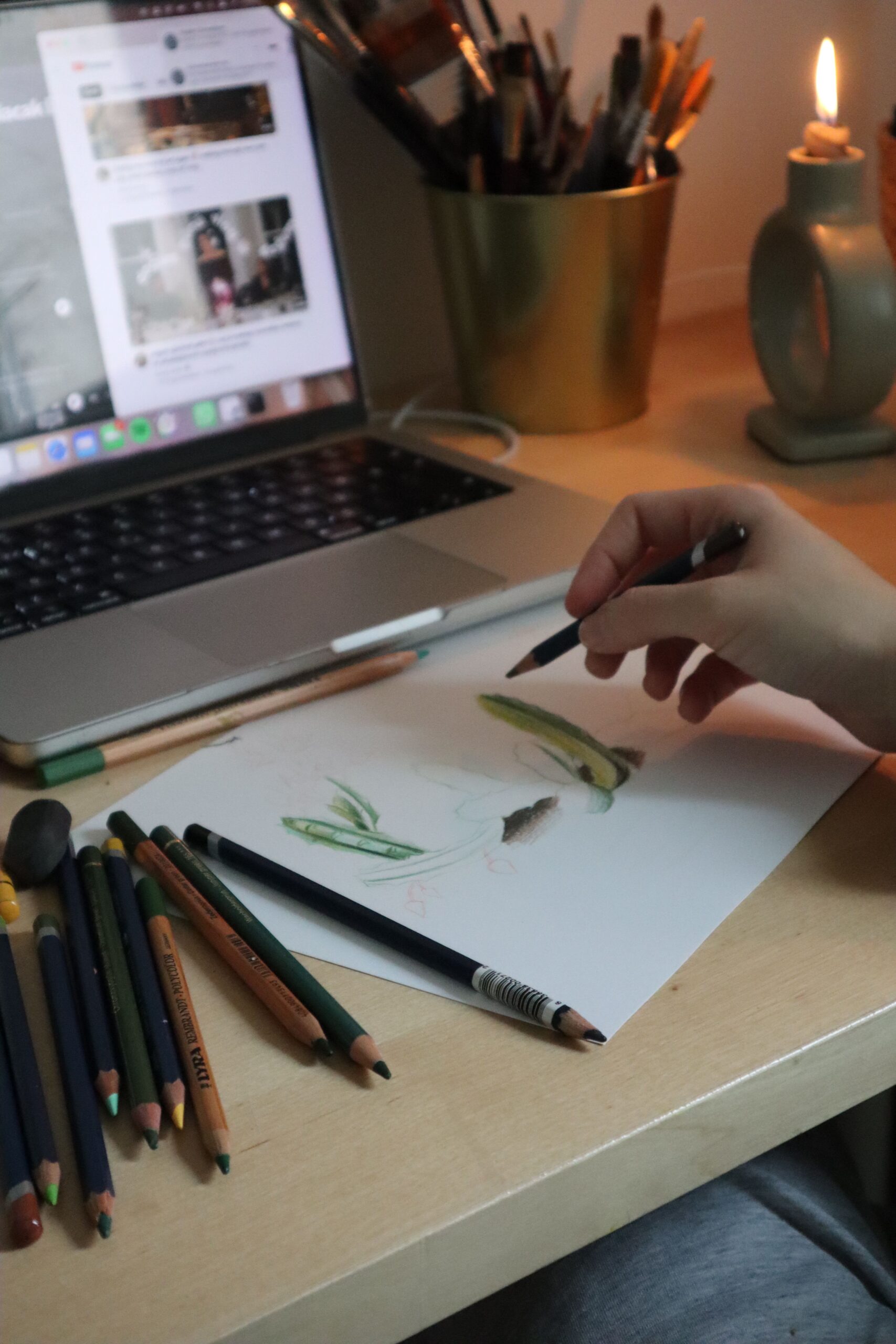 Cozy workspace with drawing pencils, sketch, and laptop lighting a creative mood.